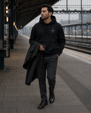 NORVEN Origin Essential Hoodie in black at a European railway station