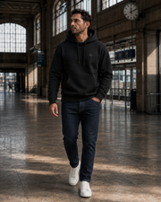 Black NORVEN Origin Essential Hoodie layered under a structured coat for travel