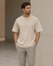 Man wearing the NORVEN Origin Heavyweight Tee in Sand with tailored trousers